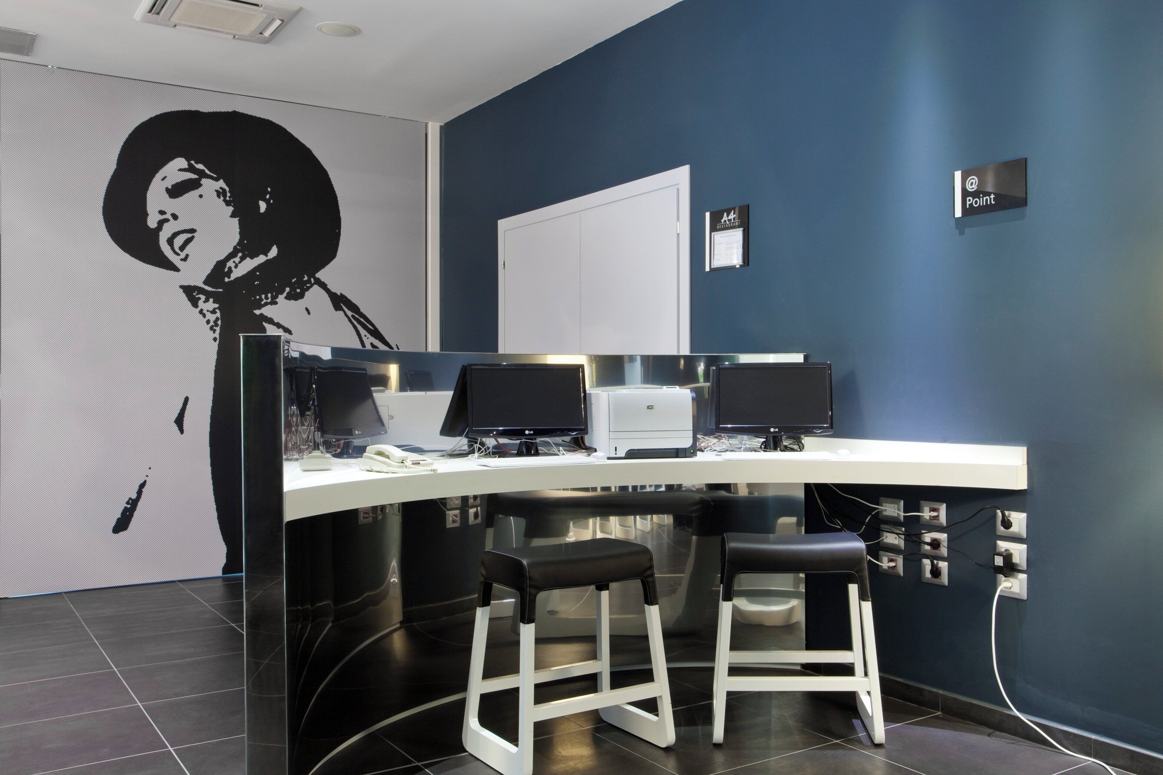 A modern office space with a curved desk, two black office chairs, a whiteboard, and a large black and white portrait on the wall.