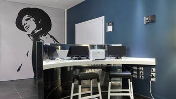A modern office space with a curved desk, two black office chairs, a whiteboard, and a large black and white portrait on the wall.