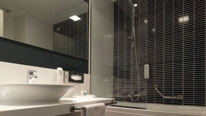 A modern bathroom with a large mirror, white sink, and a bathtub. - Holiday Inn Milan Nord Zara by IHG (Cinisello Balsamo)