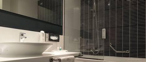 Un baño moderno con un espejo grande, lavamanos blanco y una bañera.