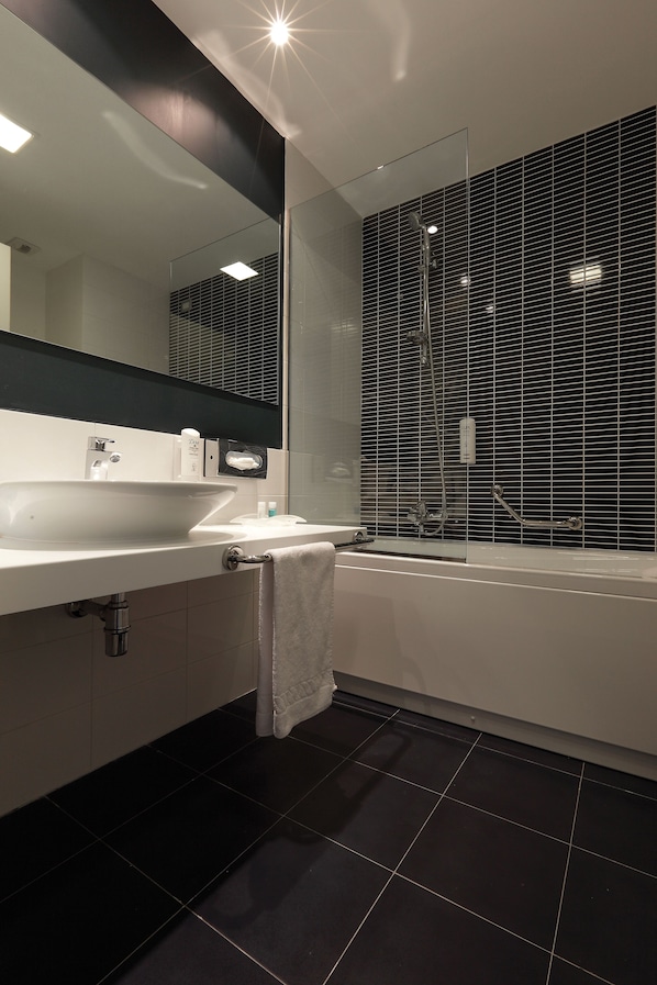 A modern bathroom with a large mirror, white sink, and a bathtub. - Holiday Inn Milan Nord Zara by IHG (Cinisello Balsamo)