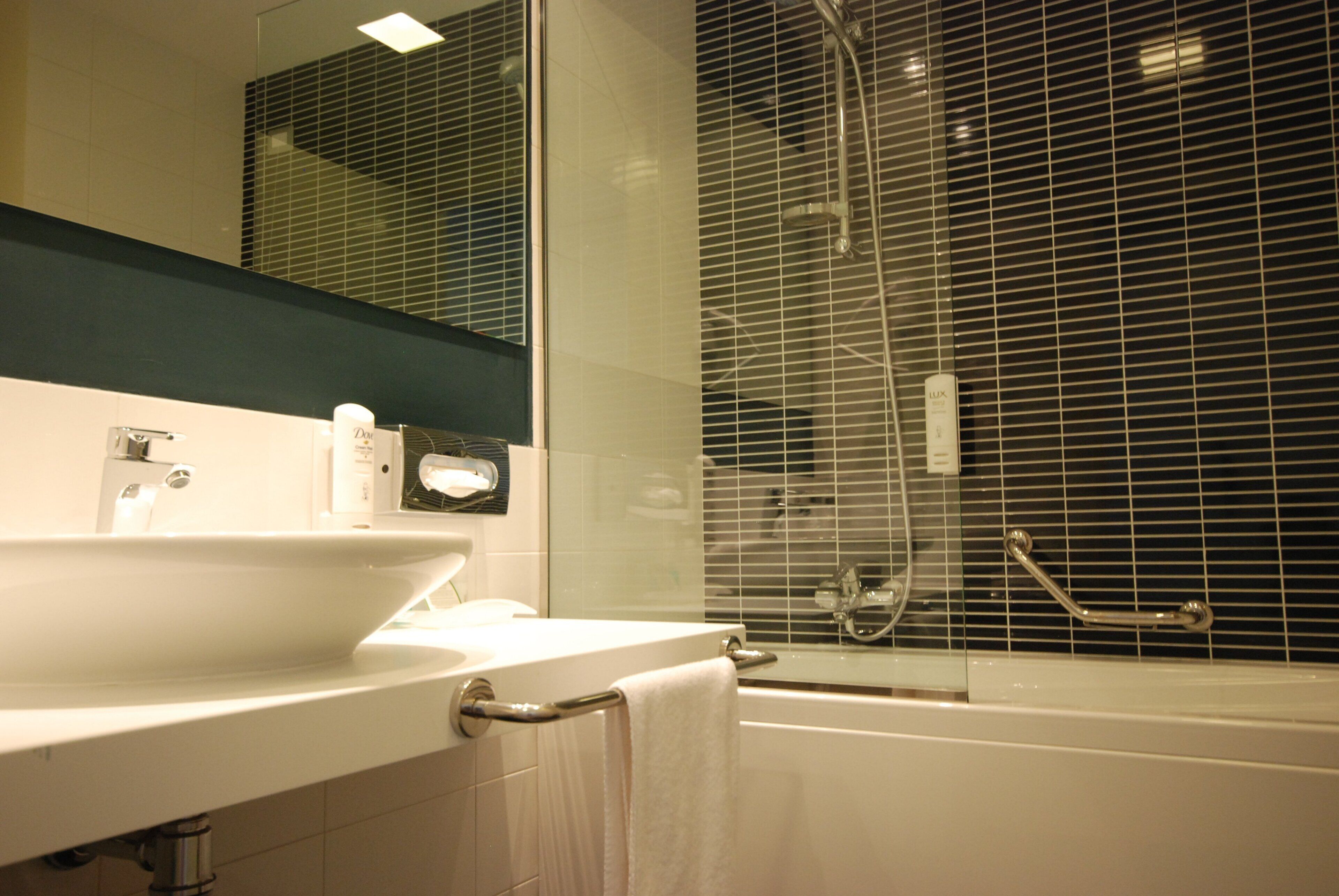Ein Badezimmer mit Waschbecken, Spiegel und Dusche.