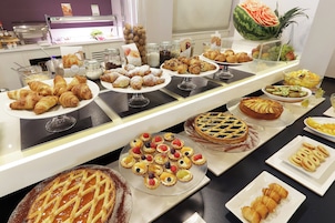 Un bufé con una variedad de pasteles, postres y frutas.