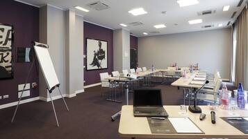 Une salle de conférence équipée d’une longue table, de chaises, d’un ordinateur portable et de matériel de présentation.