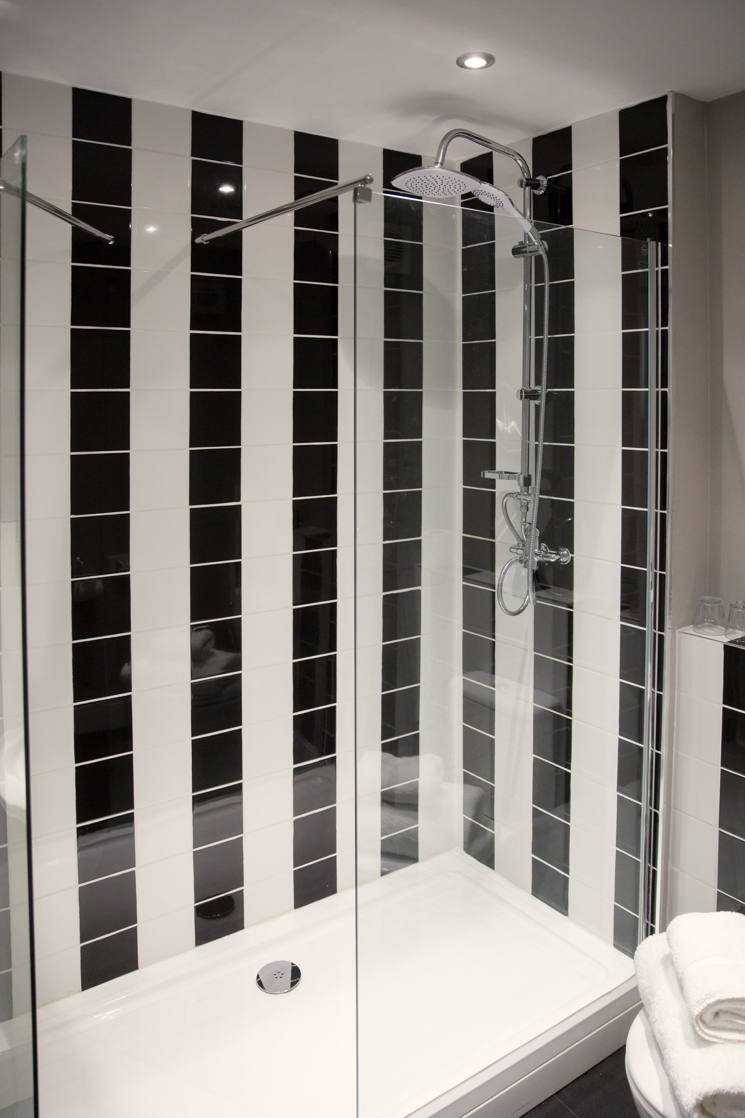 A modern shower with a glass enclosure, a handheld showerhead, and a control panel.