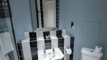 A bathroom with a white sink, mirror, and toilet.