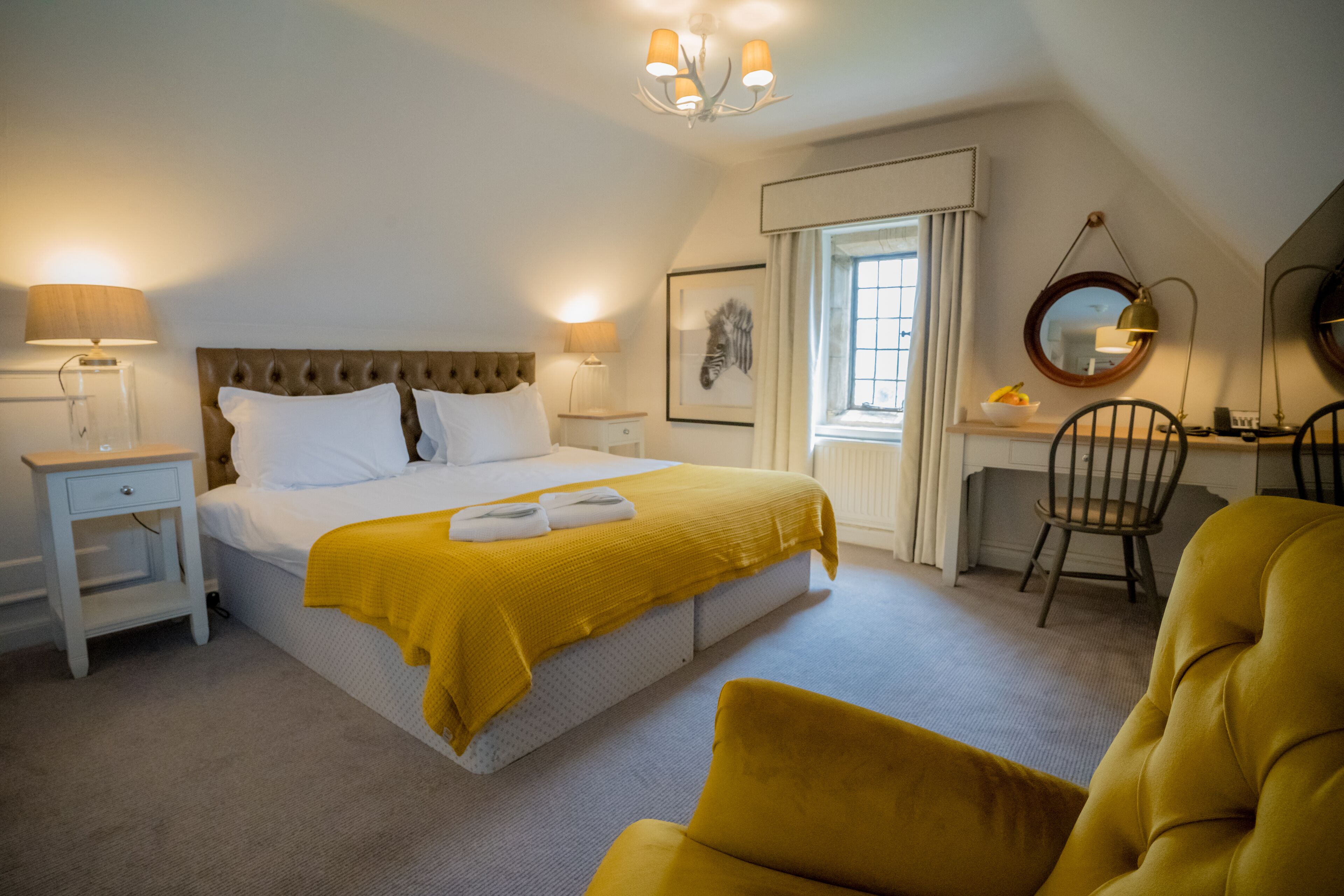 A bedroom with a large bed, bedside tables, a desk, and a chair.