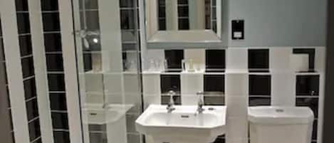 A bathroom with a glass shower enclosure, a pedestal sink, and a toilet.