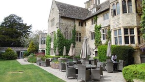 A stone building with a courtyard featuring outdoor seating and umbrellas. - Stonehouse Court Hotel (Stonehouse)