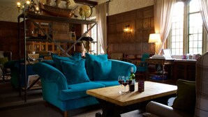 A cozy room with a teal sofa, wooden shelves, and a table with wine glasses. - Stonehouse Court Hotel (Stonehouse)