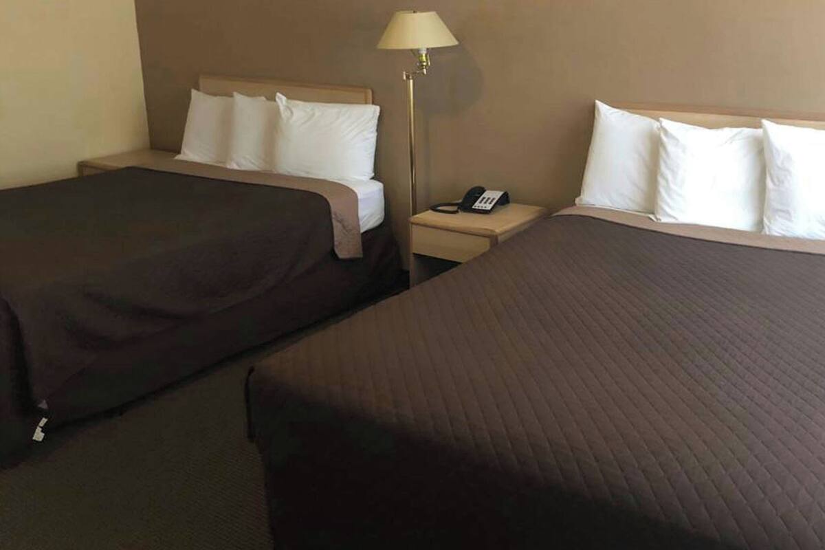 Ett hotellrum med två sängar, ett nattduksbord med en lampa och en telefon.
