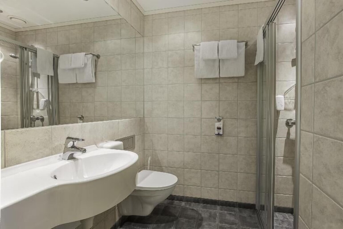 Un baño con lavamanos, inodoro y ducha.