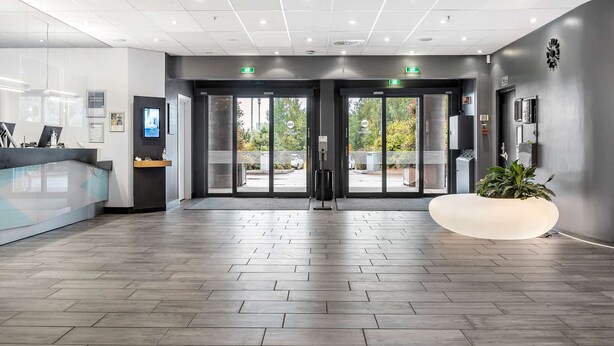 Un moderno mostrador de recepción de hotel, con pantallas digitales y una planta grande.