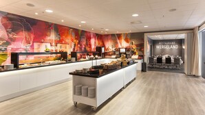 Zona de bufé con un mostrador que exhibe diferentes platillos, un mural en la pared y un letrero que indica 'Restaurant Wergeland'.