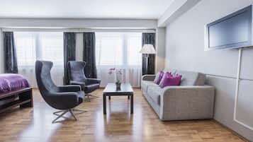 En moderne stue med sofa, to lænestole, sofabord og fjernsyn monteret på væggen.