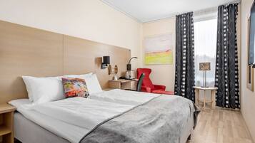 Une chambre d’hôtel avec un grand lit, un bureau, une chaise et un téléviseur.