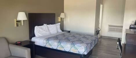 Une chambre d’hôtel avec un lit, deux lampes de chevet, un bureau, une chaise et un radiateur.