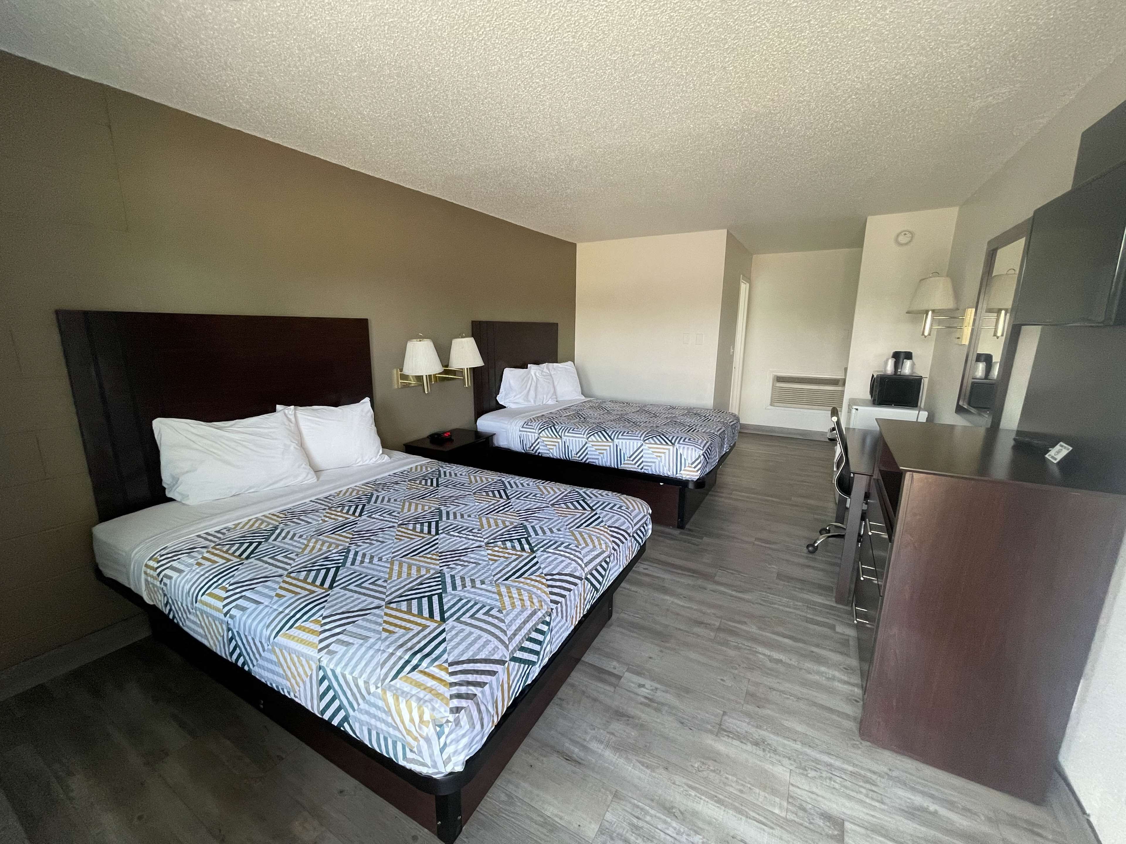 Habitación de hotel con dos camas, un escritorio, una silla y un espejo.