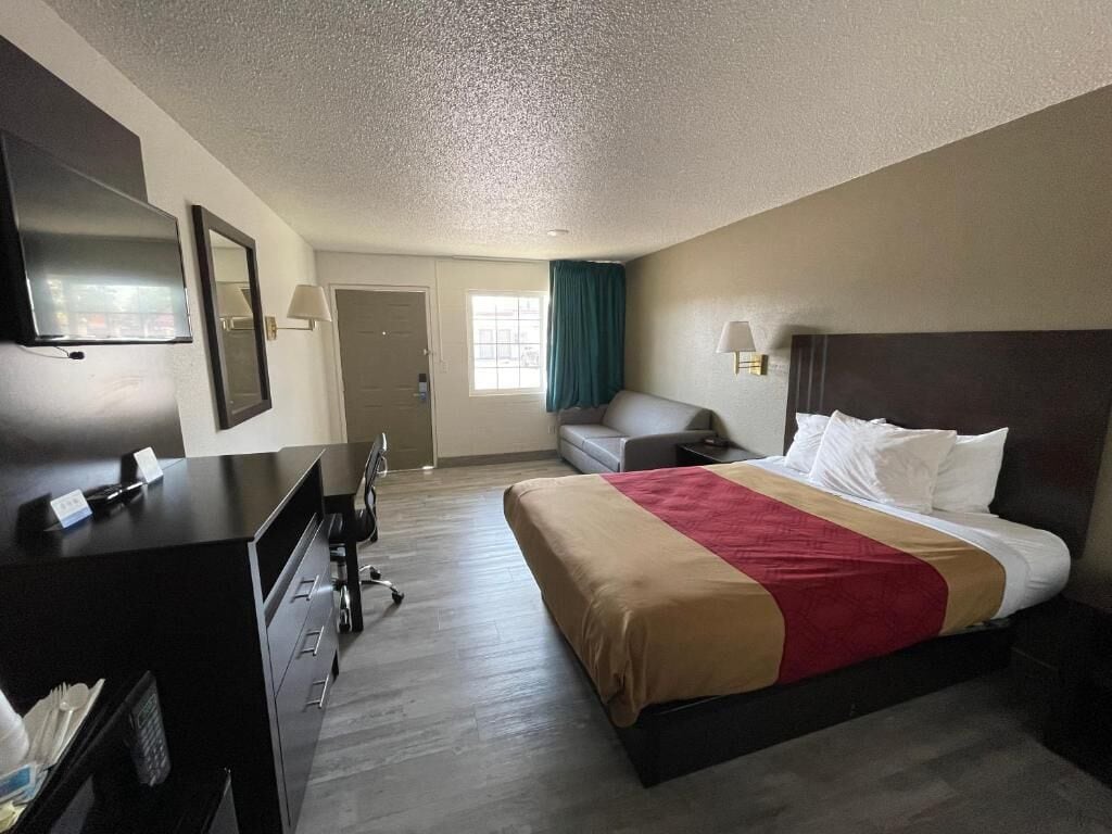 A hotel room with a bed, a desk, a chair, a television, and a window with curtains.