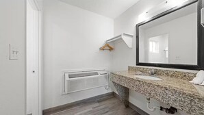A bathroom with a granite countertop, a white sink, a large mirror, and a wall-mounted heater. - Motel 6 Hermison, OR - Umatila (Hermiston)
