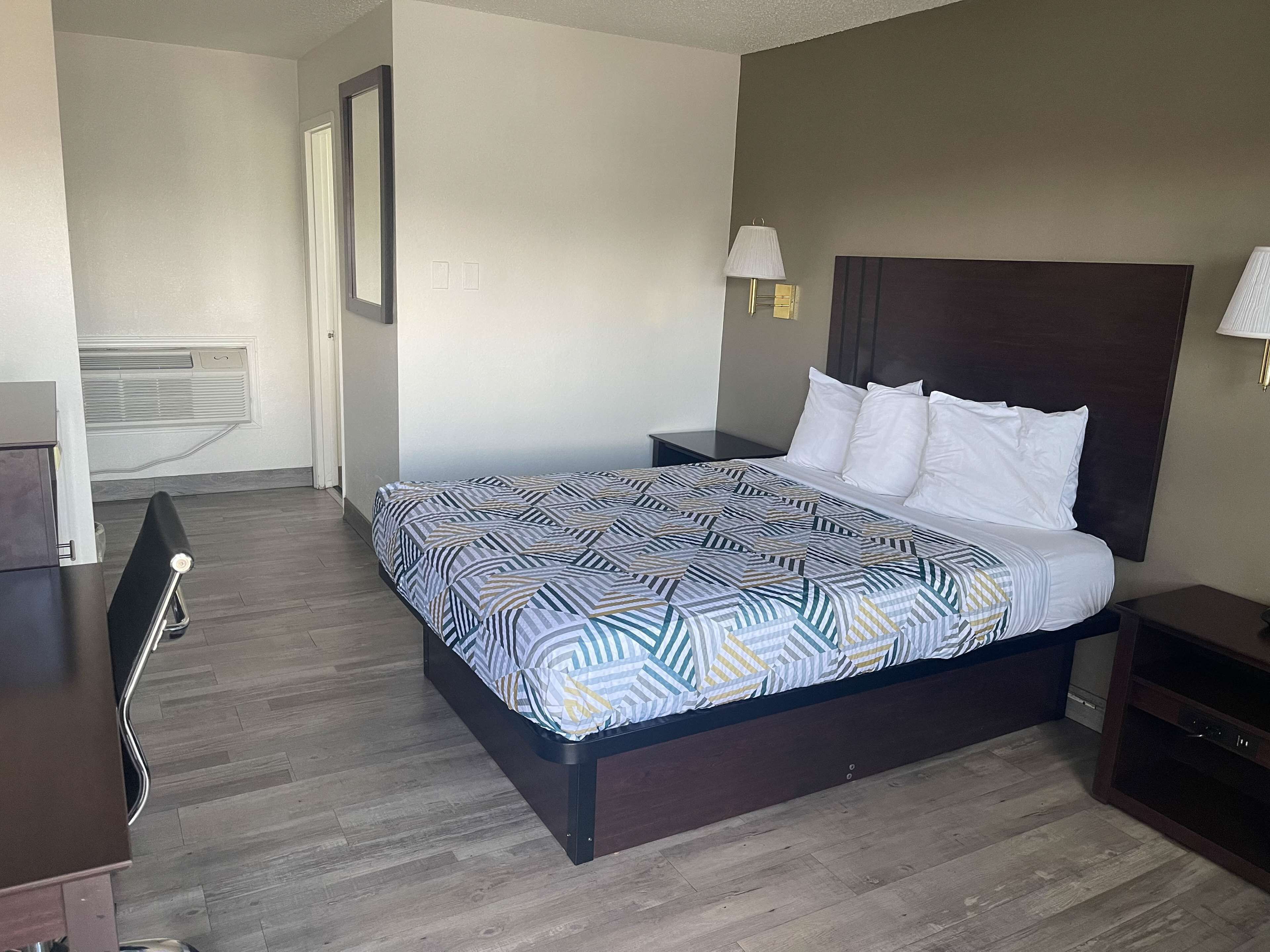 Une chambre d’hôtel avec un grand lit, une table de chevet, une chaise et un bureau.