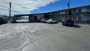 A parking lot with several cars parked in front of a two-story building with a flat roof and a small overhang. - Motel 6 Hermison, OR - Umatila (Hermiston)