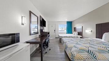 Quarto de hotel com duas camas, uma escrivaninha, uma televisão e uma janela com vista.