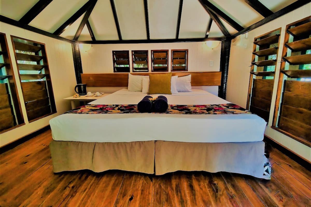 Ein großes Bett mit Holz-Kopfteil, einem Nachttisch und einer blumigen Bettdecke.