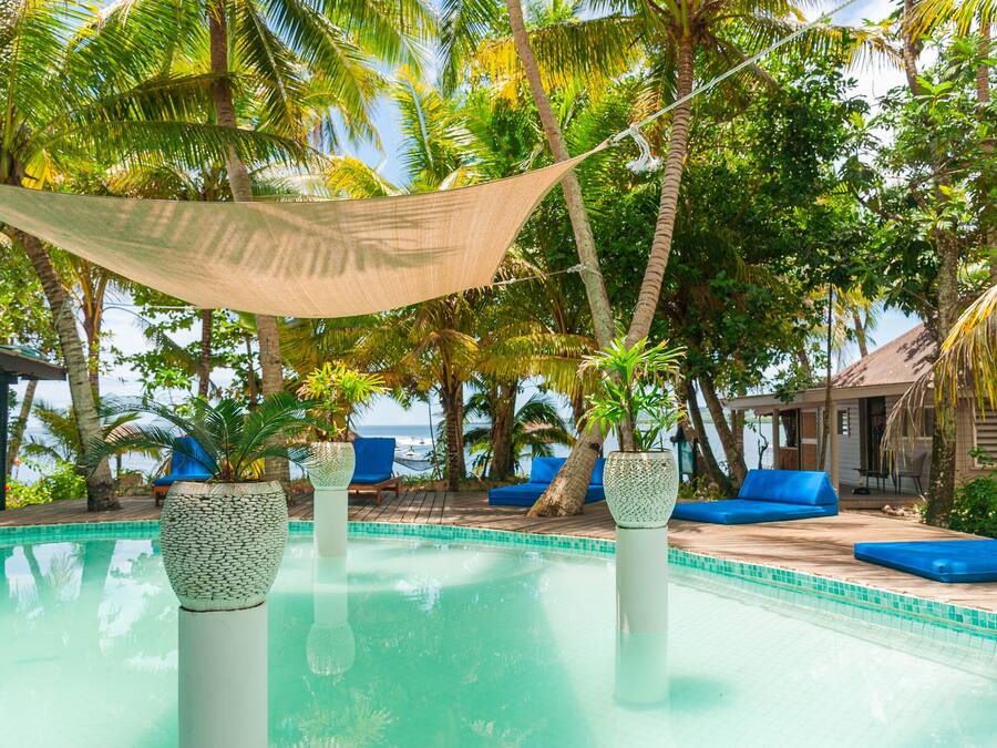 Un área de piscina con sillones de descanso, una hamaca y plantas en macetas.