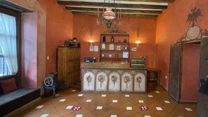 A lobby with a wooden ceiling, a reception desk with a floral design, and a wall with a bird mural. - Hotel NASS Casa del Aguila (Cuenca)