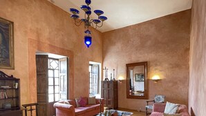 A spacious living room with wooden flooring, two pink sofas, a coffee table, and a chandelier. - Hotel NASS Casa del Aguila (Cuenca)