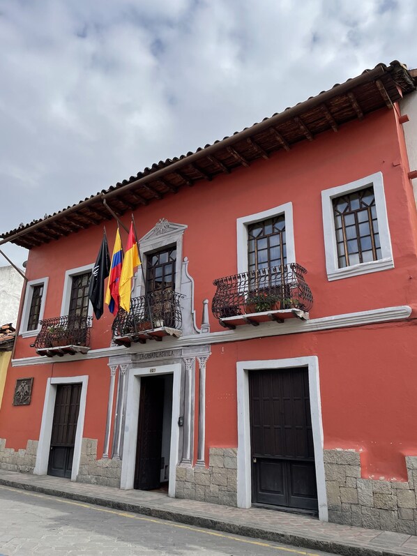 A red building with white trim, multiple windows, and balconies with wrought iron railings.