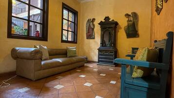 A living room with a brown sofa, a blue chair, a large window, and a tiled floor.