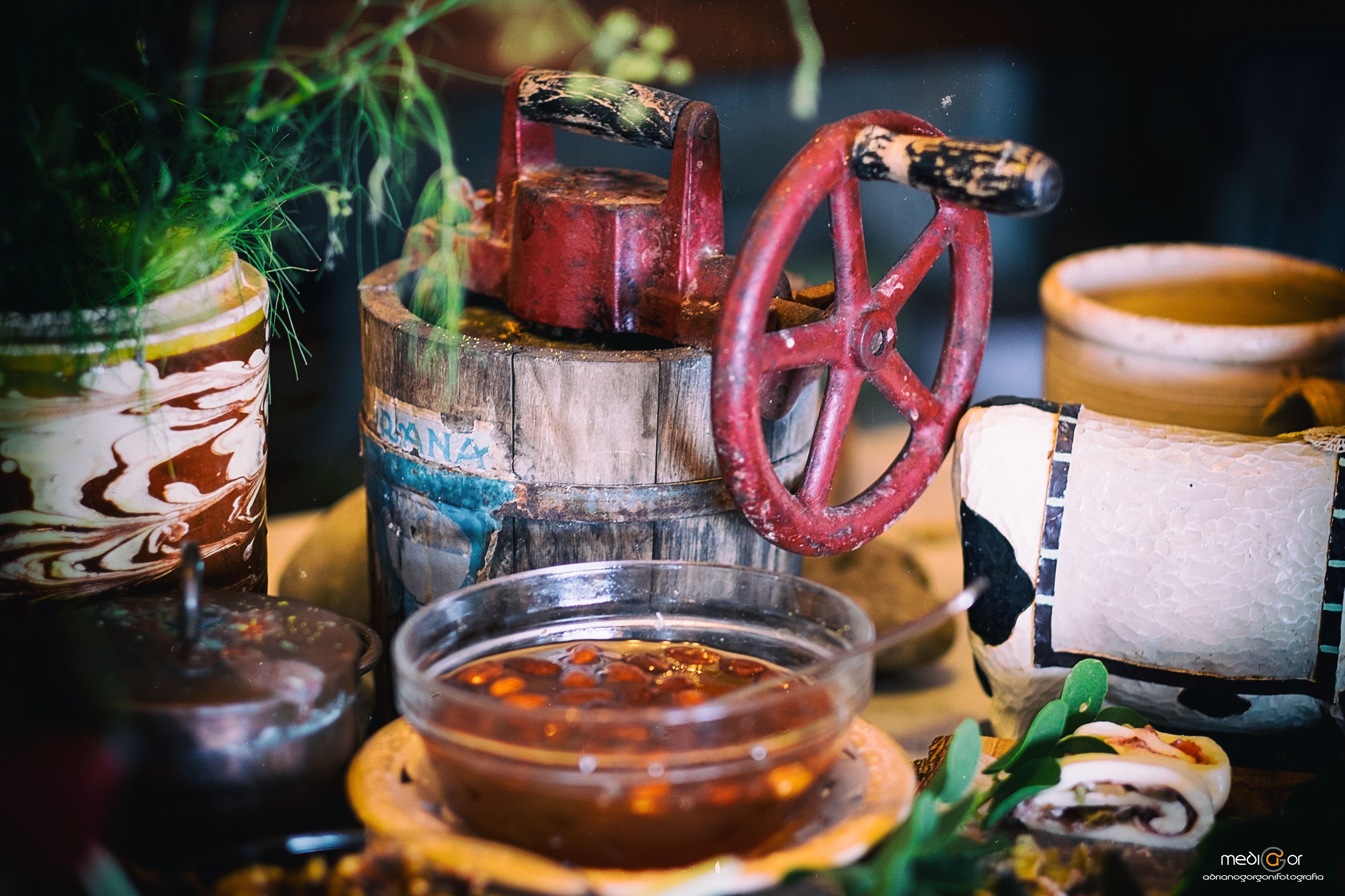 A rustic setting with a wooden barrel, a metal spigot, and a glass container with a sauce.