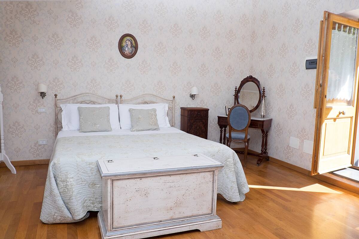 Ein Schlafzimmer mit Bett, Kommode, Stuhl und Spiegel.