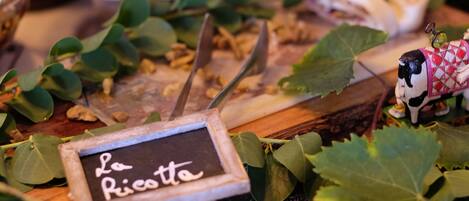 A cheese board with a sign reading "La Ricotte" surrounded by leaves and a small figurine.
