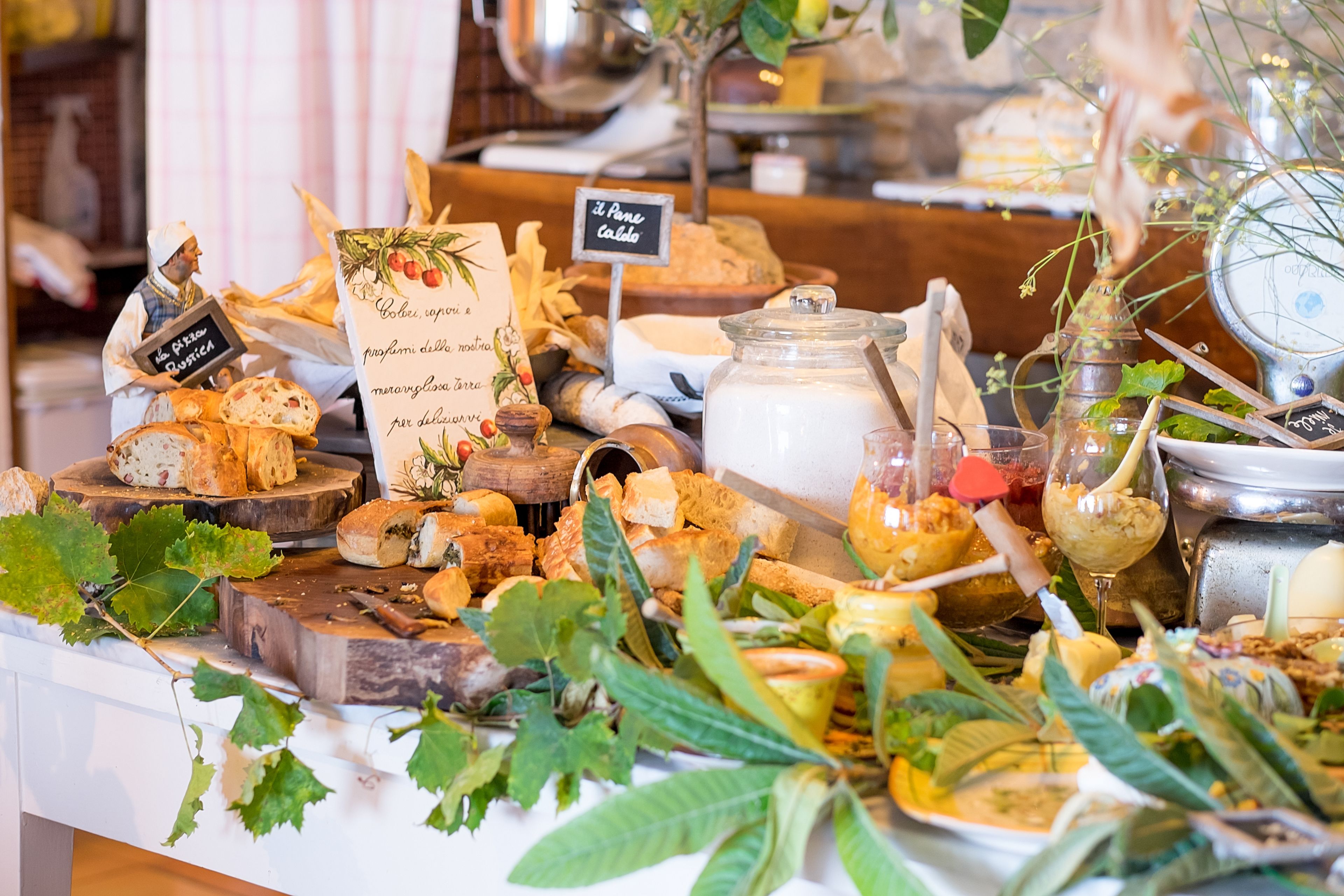 A cheese and wine tasting setup with various cheeses, a wine glass, and a sign indicating 'Il Pane Caldo'.