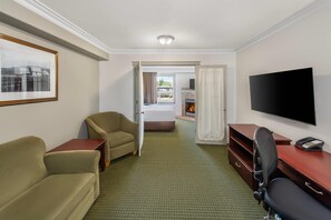 A hotel room with a bed, a TV, a desk with a phone, and two chairs. - Quality Inn & Suites Whitecourt (Whitecourt)