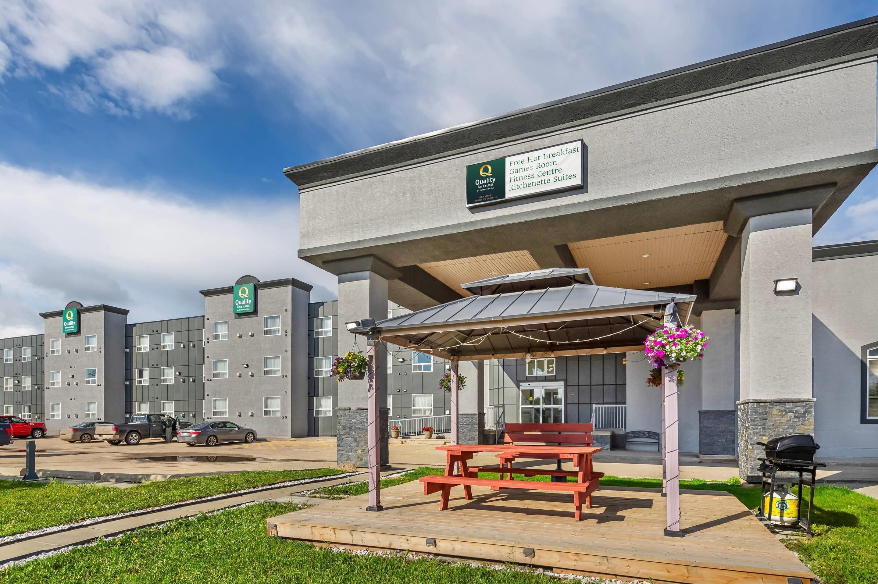 Un hotel con zona de estar exterior cubierta, gimnasio y kitchenette.