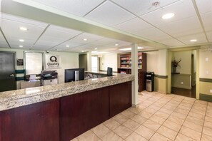 A hotel reception area with a reception desk, a security camera, a Dell computer, and a Coca-Cola refrigerator. - Quality Inn & Suites Whitecourt (Whitecourt)