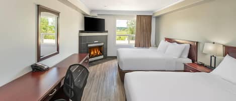 Habitación de hotel con dos camas, un escritorio con silla, chimenea, televisor y ventana con cortinas.