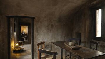 Un comedor rústico con una mesa y sillas de madera, una vela en un candelabro y una ventana con luz natural.