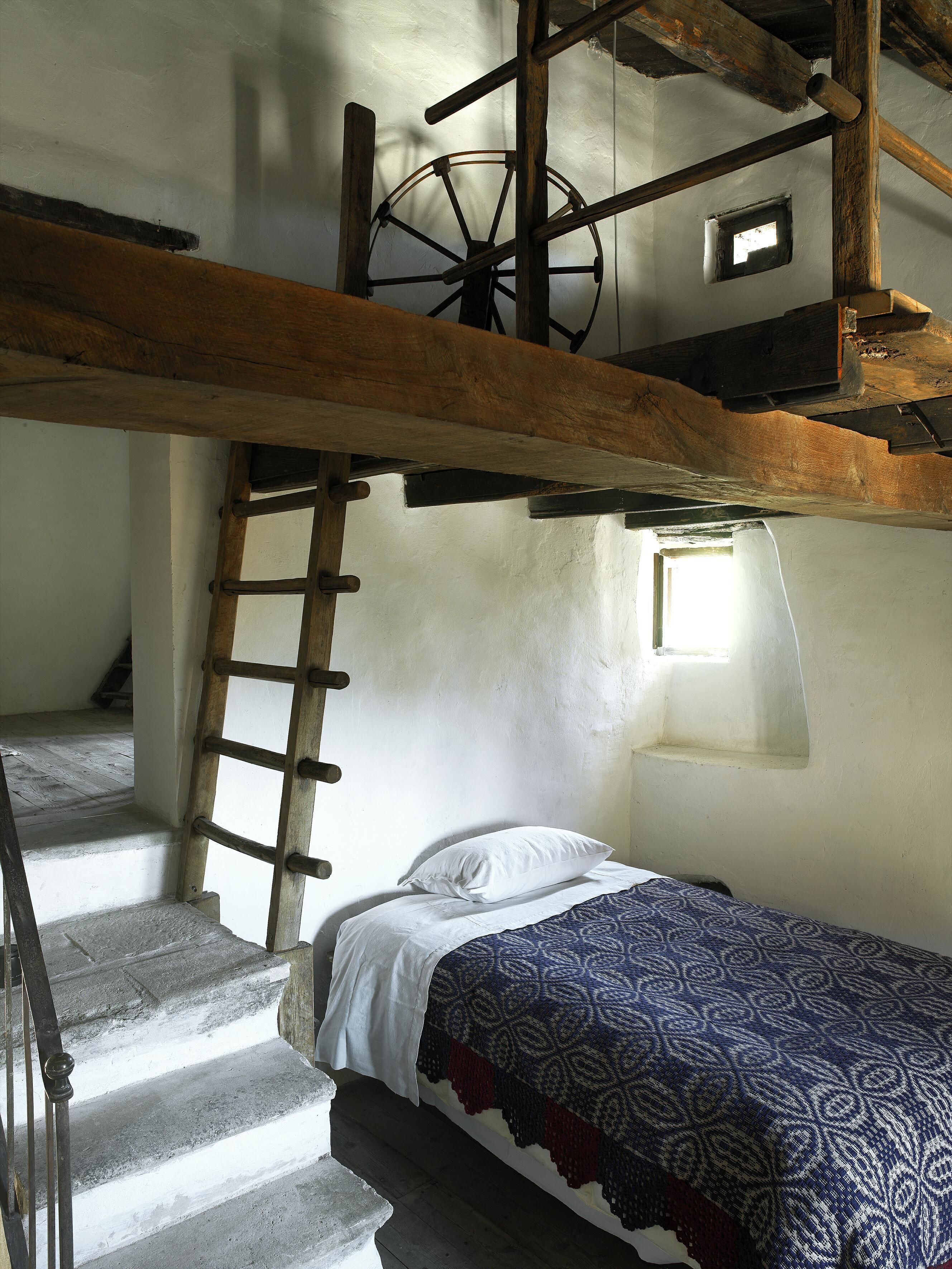 A rustic room with a bunk bed, a wooden ladder, and a small window.