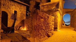 A stone-walled courtyard with a wooden cart, a small table, and a candle on the ground. - Sextantio Albergo Diffuso (Santo Stefano di Sessanio)