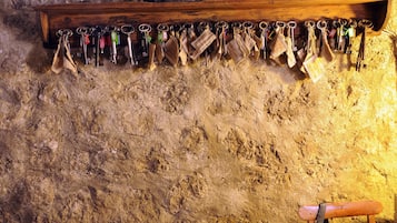 A wooden shelf with a collection of keys hanging on a textured wall.