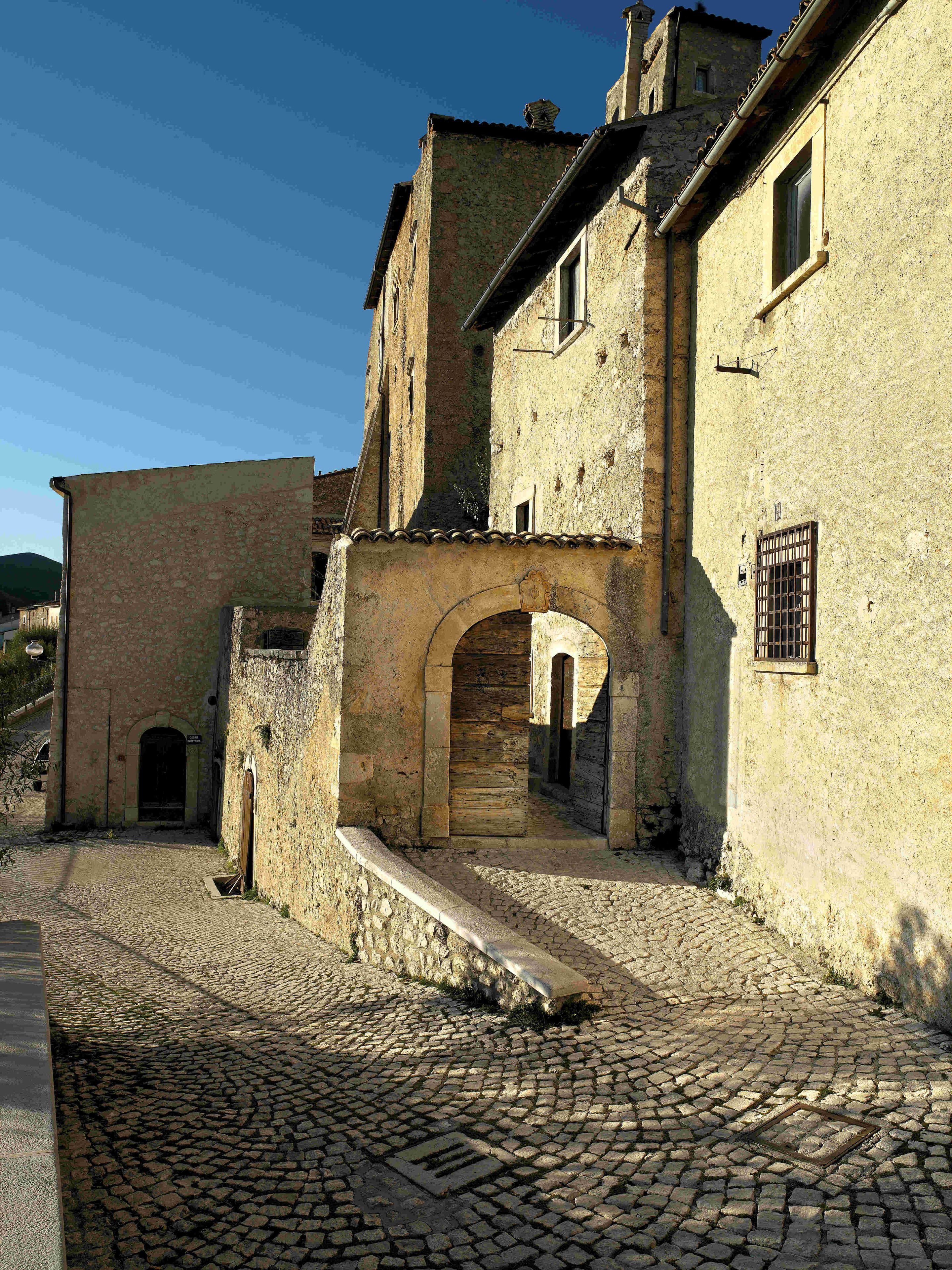 Una strada acciottolata che conduce a un edificio storico con un ingresso ad arco e una piccola finestra.