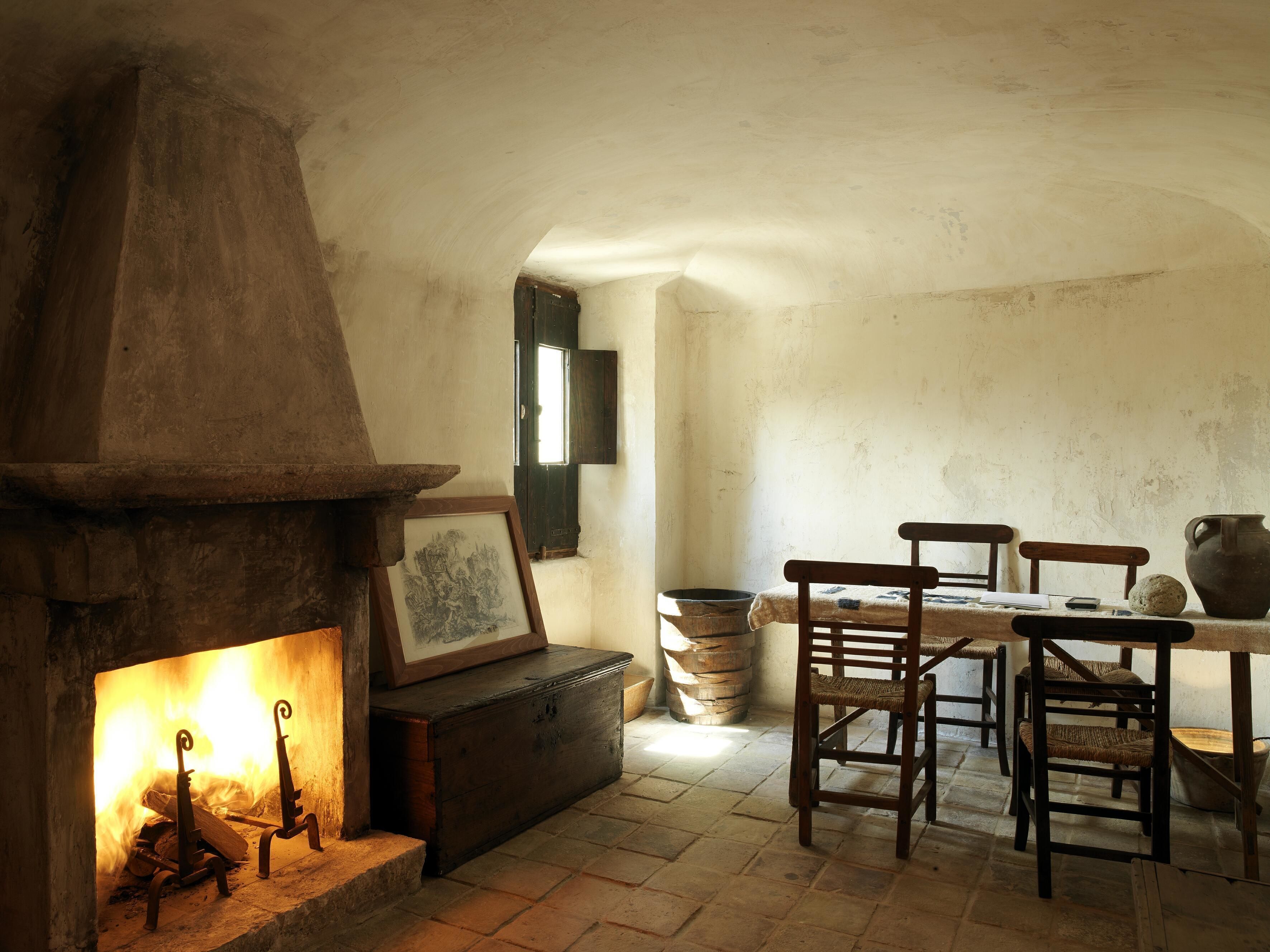 A rustic room with a fireplace, wooden furniture, and a stone wall.