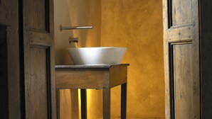 A rustic bathroom with a wooden table and a white basin. - Sextantio Albergo Diffuso (Santo Stefano di Sessanio)
