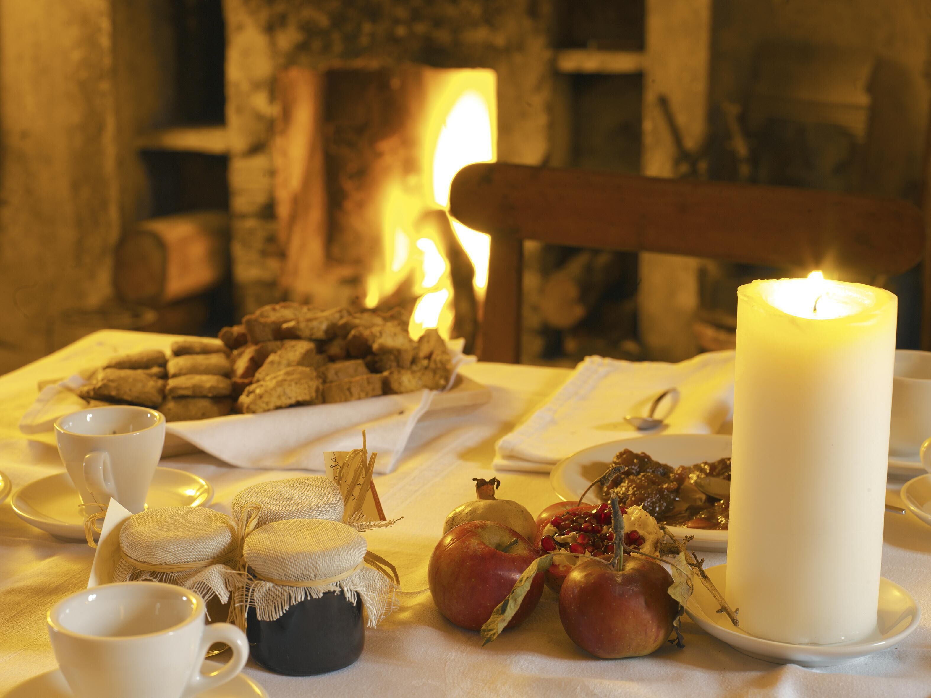 A table set with candles, apples, and a plate of cookies.