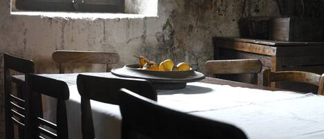 A rustic dining room with a table set for two, featuring a plate of lemons and a wicker basket.